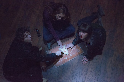 (L to R) Pete (DOUGLAS SMITH), Laine (OLIVIA COOKE) and Sarah (ANA COTO) play the game in Ouija, a supernatural thriller about a group of friends who must confront their most terrifying fears when they awaken the dark powers of an ancient spirit board. Photo Credit: Matt Kennedy/Universal Pictures Copyright: 2014 Universal Studios. ALL RIGHTS RESERVED.