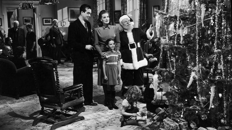 (Left to right) Actors John Payne, Maureen O'Hara, Edmund Gwenn, and young Natalie Wood stand before a Christmas tree in a still from director George Seaton's film, Miracle on 34th Street.